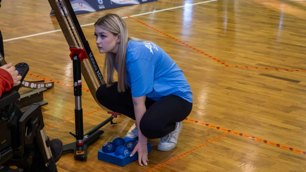 Oliwia Malczewska z AKSON Zamość jako operator rampy BC3 podczas Mistrzostw Polski Boccia 2025, przygotowująca niebieskie bile do zagrania.