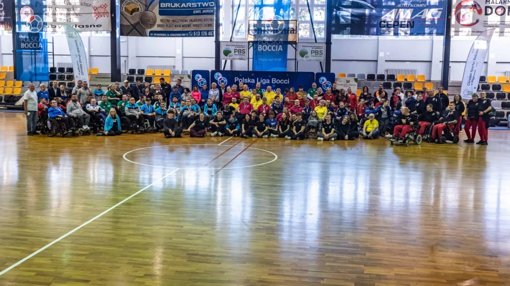 Panoramiczne zdjęcie uczestników Mistrzostw Polski Boccia 2025 ustawionych wzdłuż boiska na pamiątkową fotografię.