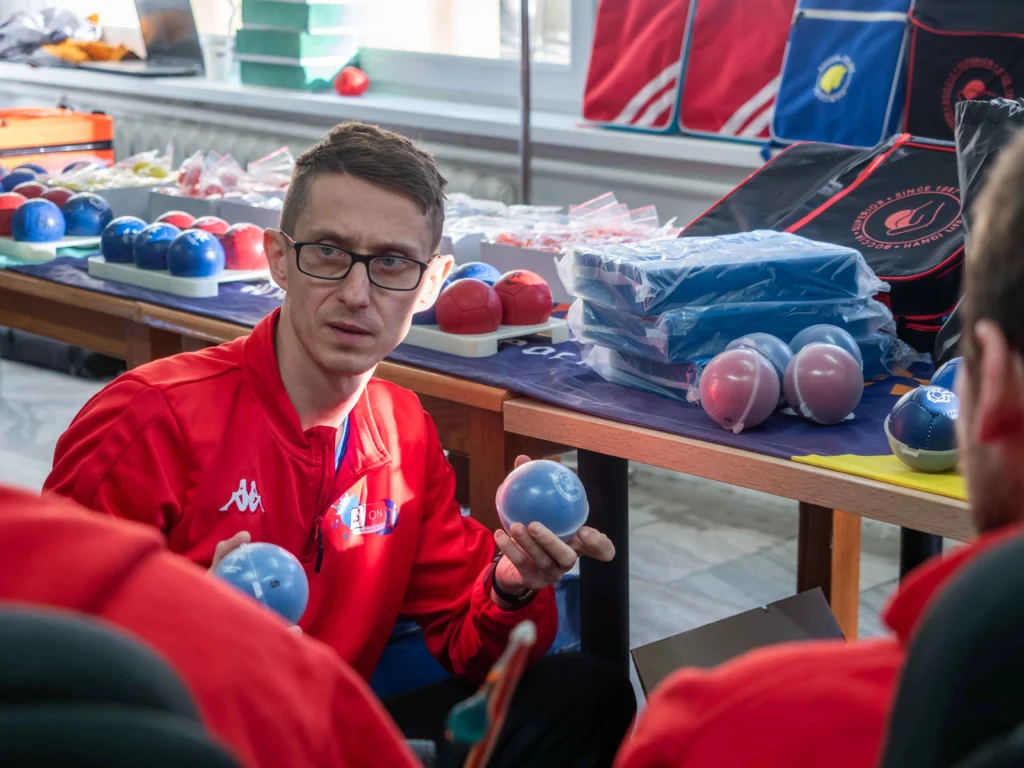 Dariusz Borowiec prezentuje i omawia piłki boccia przy stoisku ze sprzętem podczas turnieju.