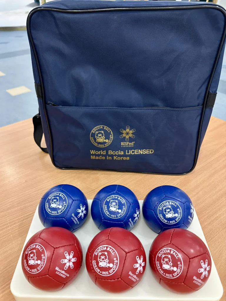 Zestaw licencjonowanych piłek Dream·Ree Sports w kolorach czerwonym i niebieskim prezentowany na tacy wraz z torbą World Boccia Licensed.