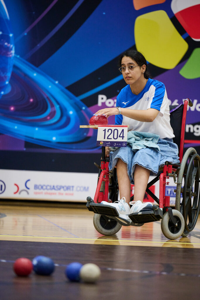 Zawodniczka boccia podczas rzutu, w tle baner BocciaSport.com