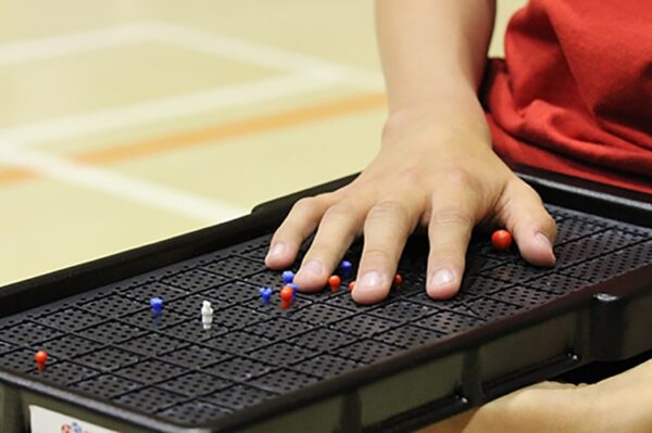 Zawodnik odczytuje dłonią położenie bil na dotykowej siatce Boccia Touch Grid