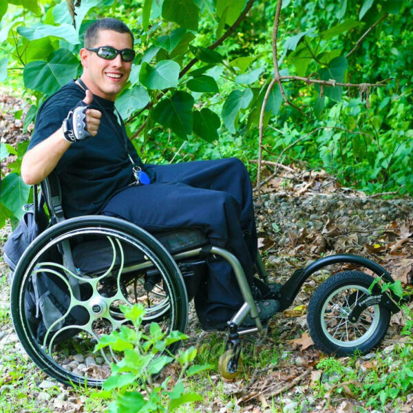 Mężczyzna na wózku z FreeWheel w terenie wśród zieleni